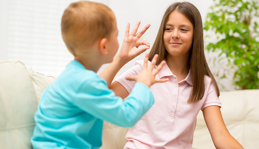 Brother and sister learn sign language at home.